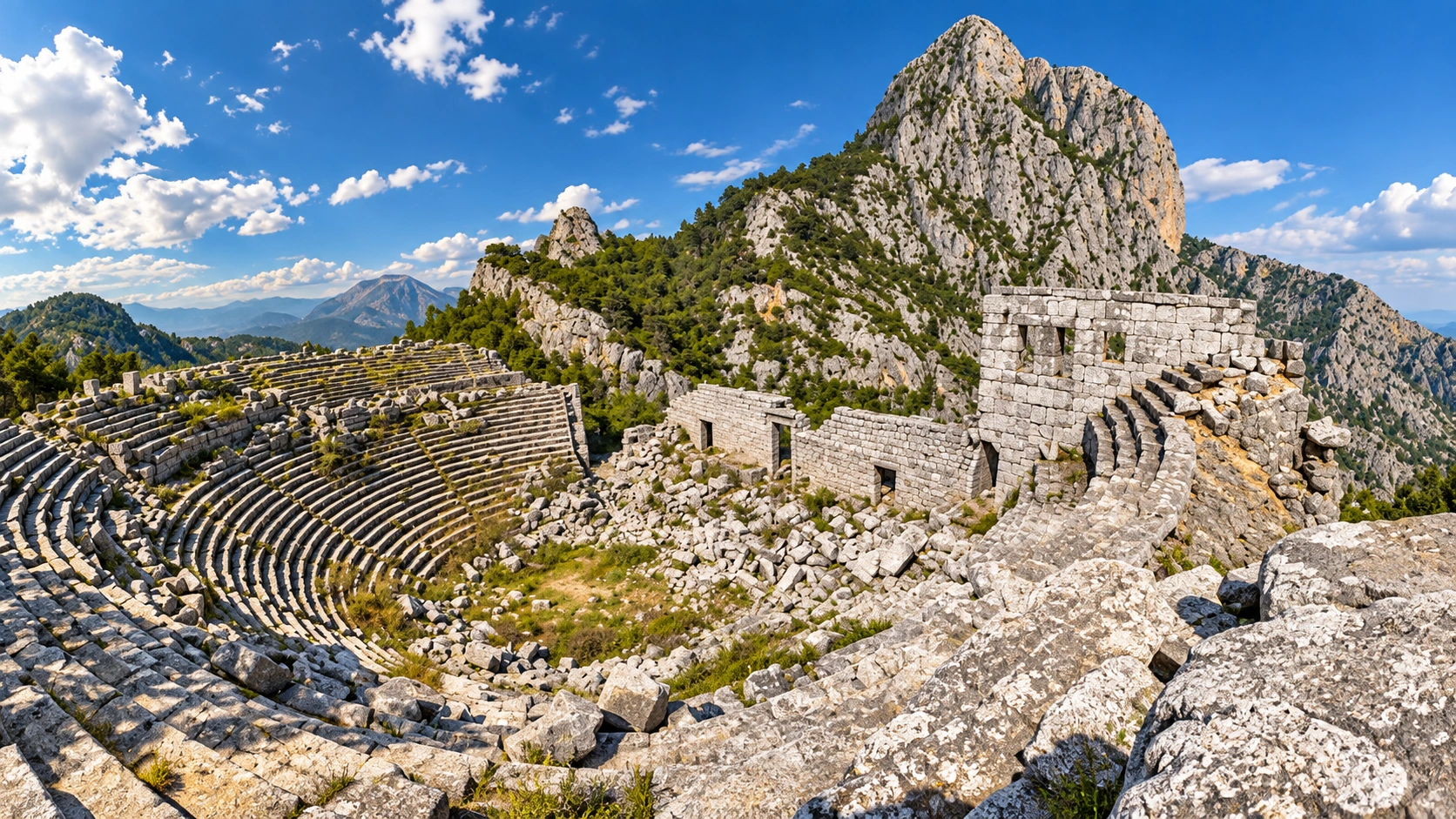 Wide view of the Termessos theatre cavea set against the Güllük Dağı mountain ridge