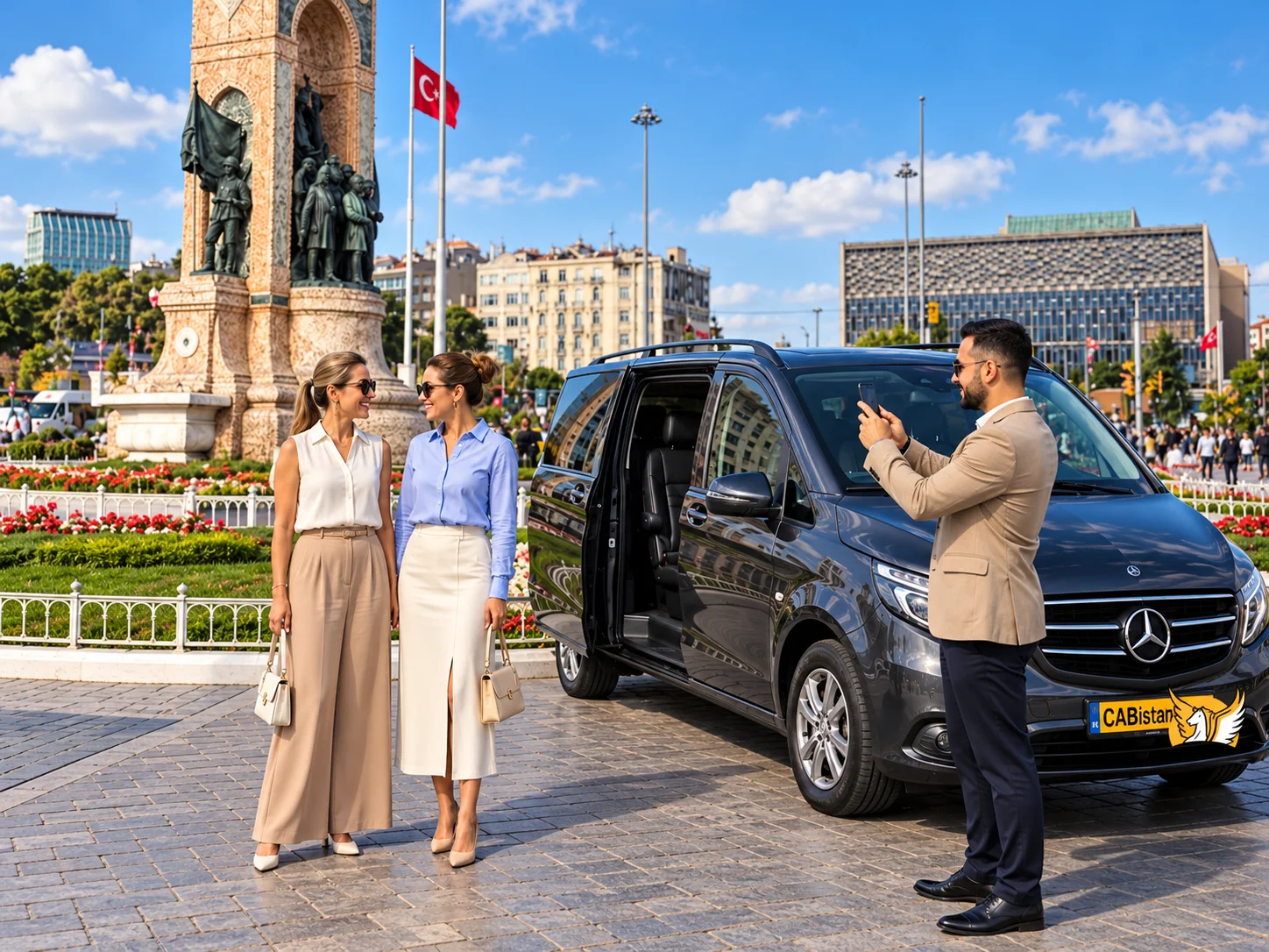 身穿米色西装外套的 Cab Istanbul 专业司机在塔克西姆广场共和国纪念碑旁，为站在黑色奔驰 Vito 商务车旁微笑的两位女旅客用手机拍照