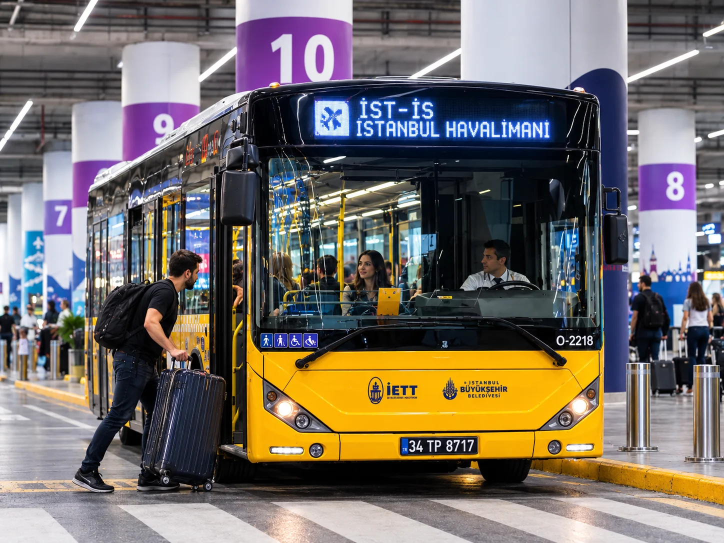 Gelb-schwarzer öffentlicher IETT-Linienbus der Stadtverwaltung Istanbul an den nummerierten Haltestellenbuchten des Flughafens Istanbul mit einem Reisenden und großem Koffer